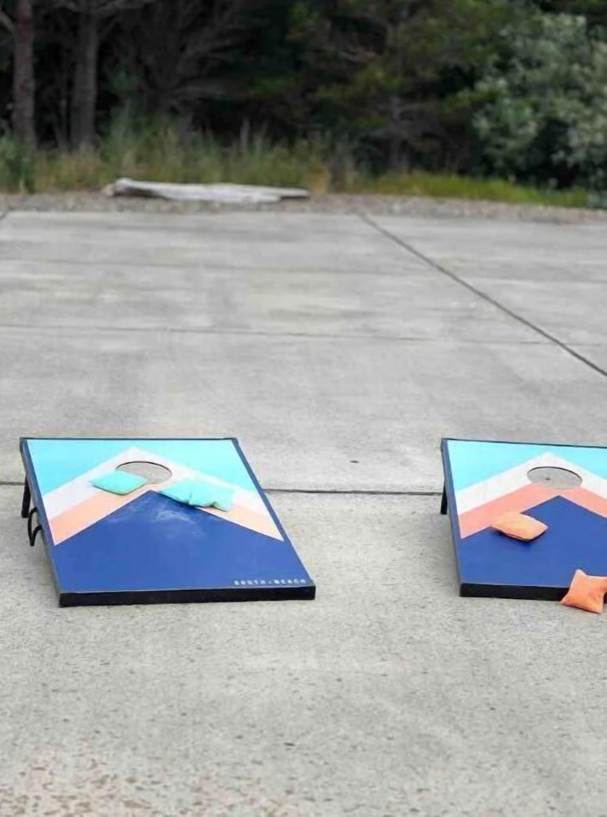 Two small tables with a colorful design on top, placed on a concrete surface outdoors.