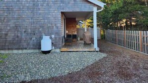 Een huis met een overdekte veranda, een witte boiler en een houten terras.