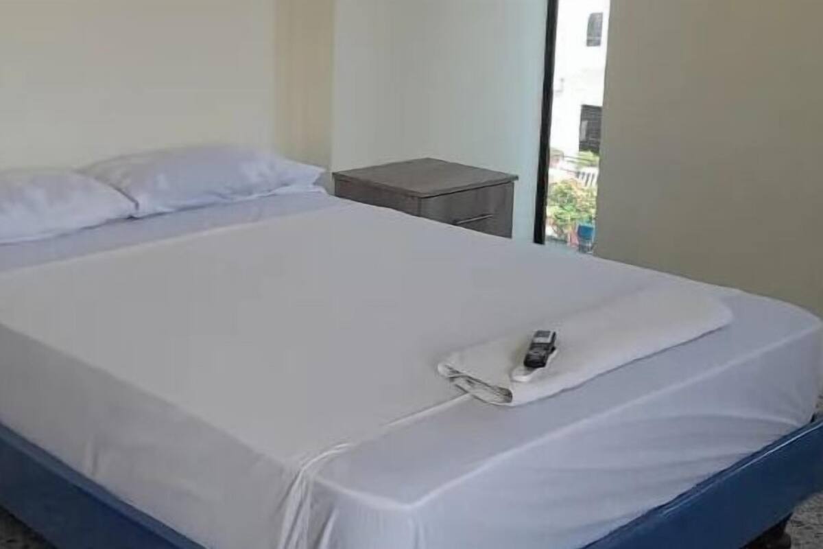 Habitació individual amb un taulell de nit, un armari de fusta i una finestra que donava a l'exterior.