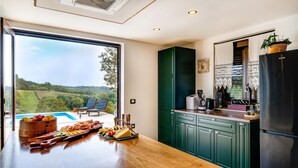 Una cocina con encimera de madera, vistas a una piscina y un armario verde.