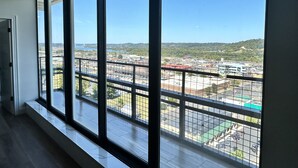 A room with large windows offering a view of a cityscape, including a bridge and industrial buildings. - Encore Suite 1 @ The Skytower Penthouse  (Ashland)