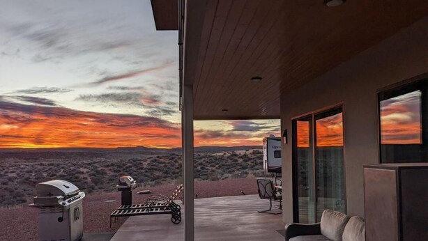 Un patio moderno al aire libre con vistas a una puesta de sol sobre un paisaje desértico.
