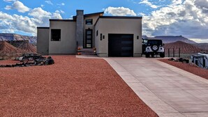 Una casa moderna con garaje, entrada para vehículos y un Jeep estacionado al frente.