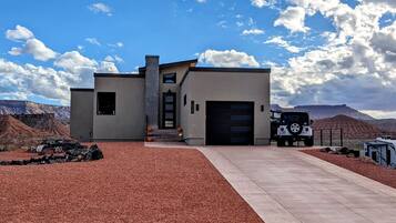 A modern house with a garage, a driveway, and a Jeep parked in front.