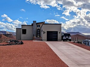 A modern house with a garage, a driveway, and a Jeep parked in front. - Cozy Studio in Virgin (Virgin)