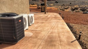 Un patio al aire libre con tres unidades de aire acondicionado, un camino de hormigón y vistas a un paisaje montañoso.