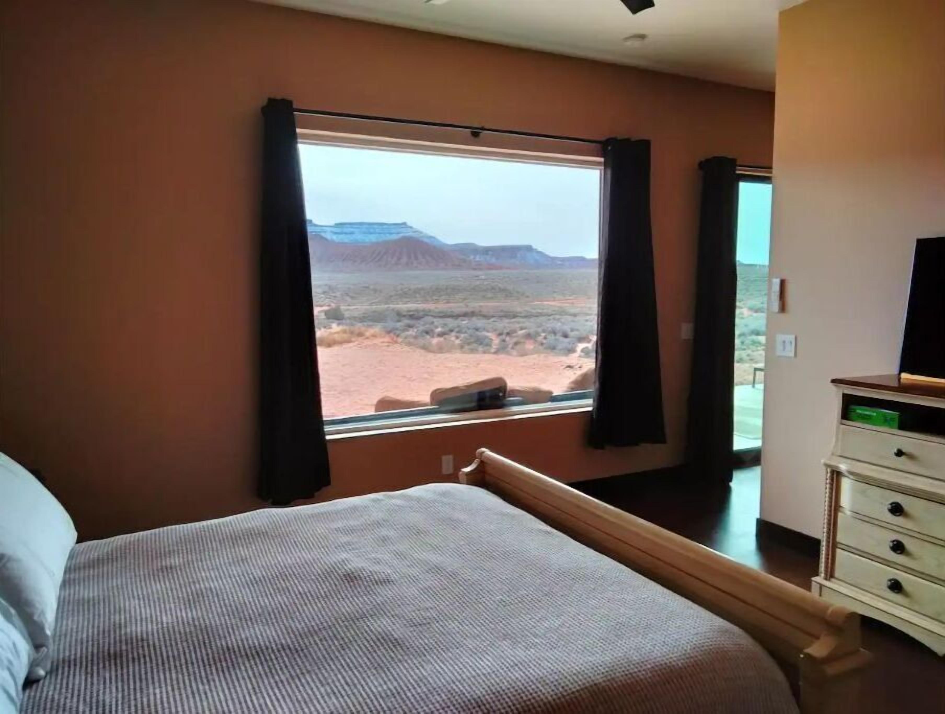 Un dormitorio con un ventanal que ofrece vistas al paisaje desértico.
