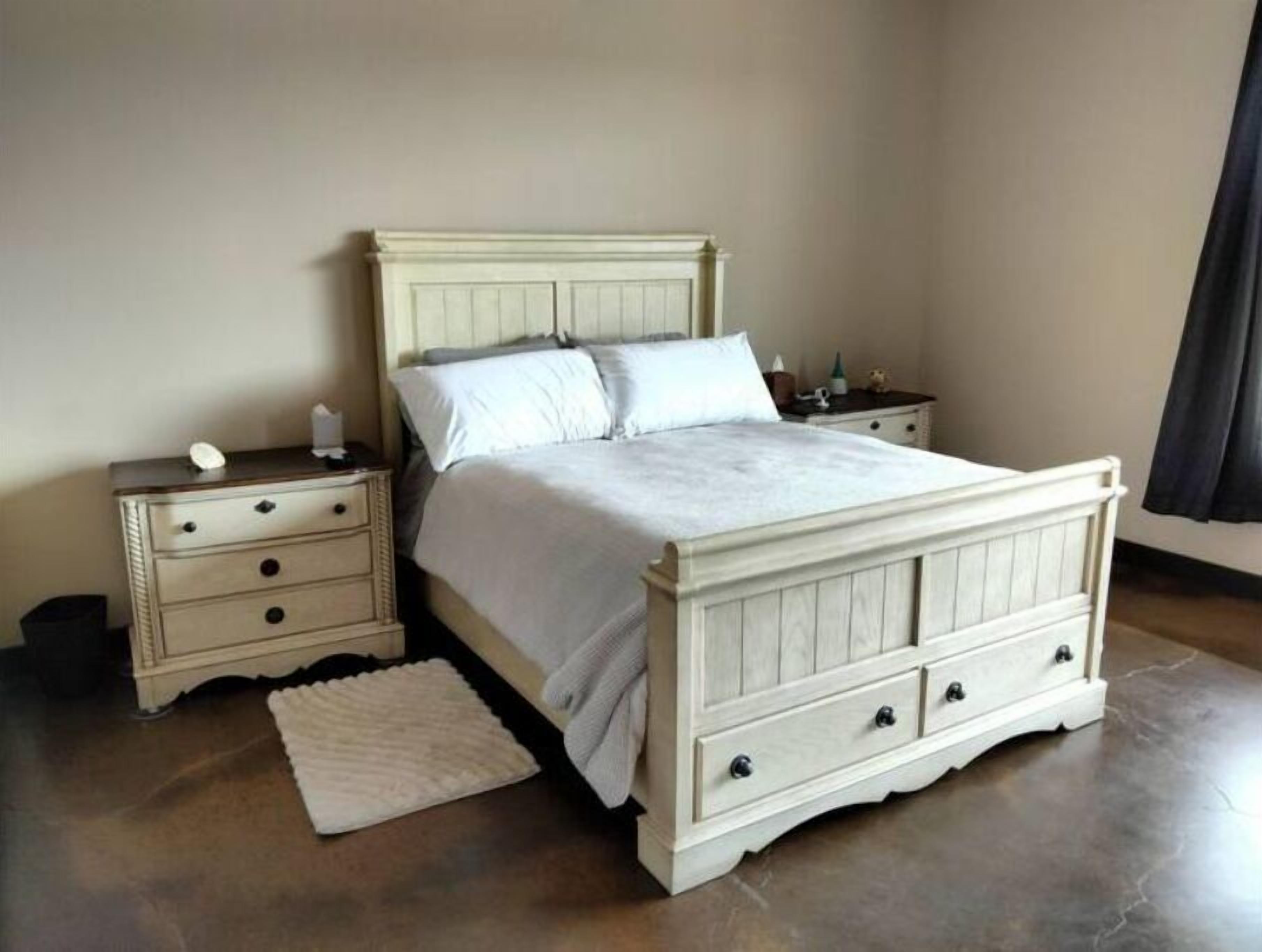 Un dormitorio con cama, mesitas de noche y alfombra.