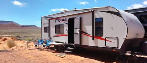 Un camper parcheggiato nel deserto sotto un cielo sereno.