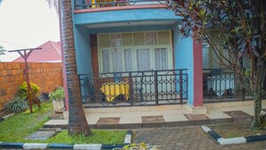 A residential building with a balcony, a potted plant, and a tiled walkway. - Quinta Nova Hotel (Kigali)