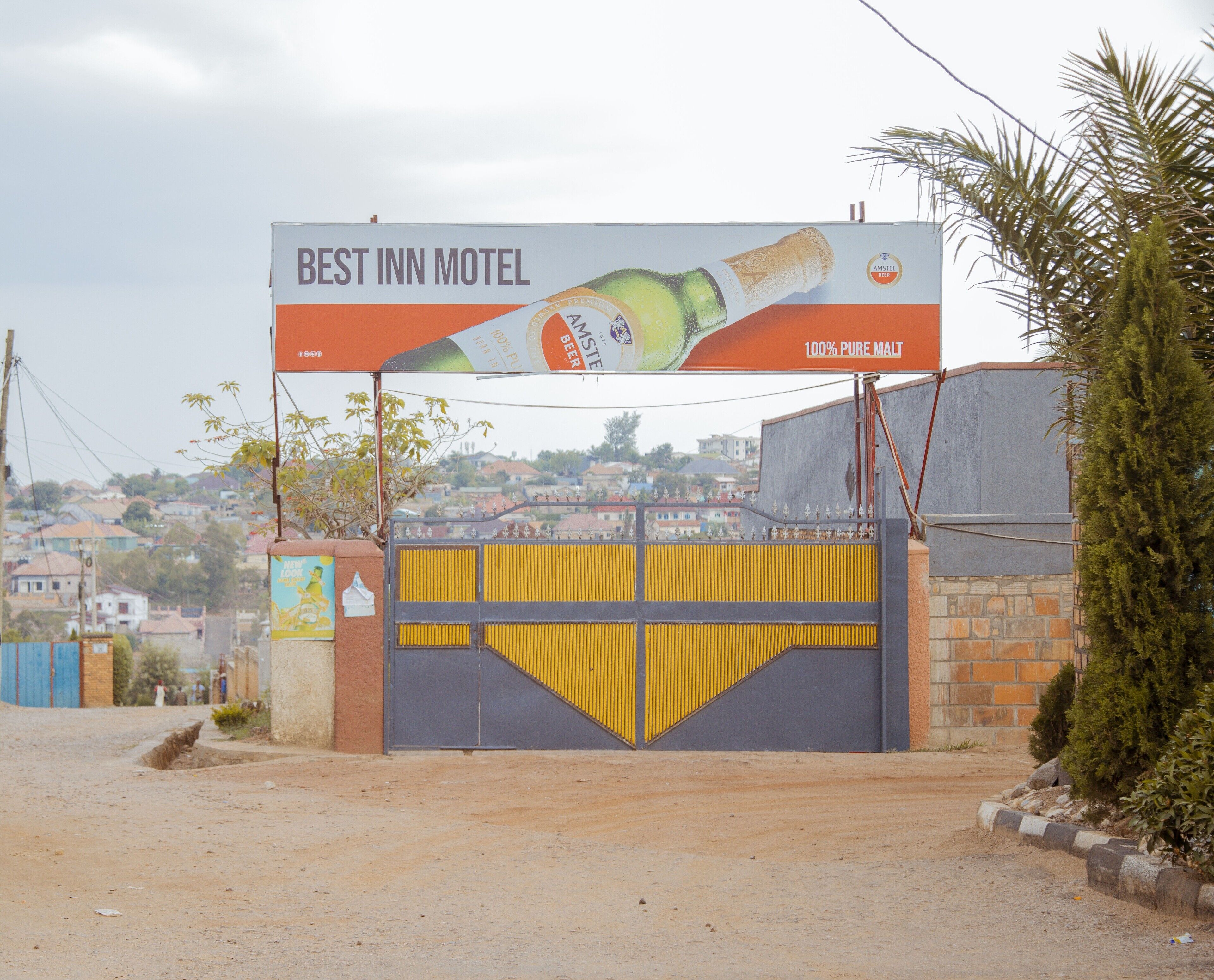 A gated entrance to a building with a large billboard advertising a hotel and a beer brand.