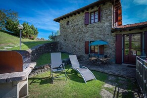 Experience the serene charm of this rustic stone building, featuring a stone staircase, wooden door, and tranquil patio area with outdoor seating.