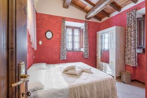 Cozy retreat with a bed, wardrobe, and mirror, set against a red accent wall.