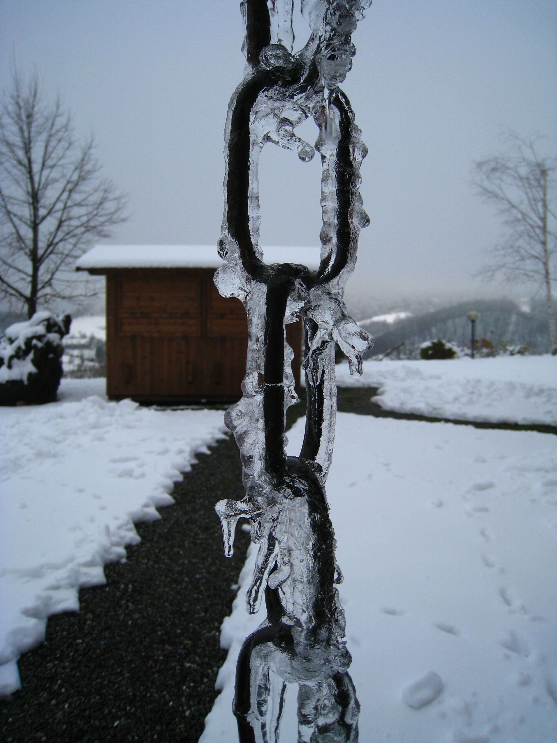 A snow-covered landscape with a wooden cabin in the background.