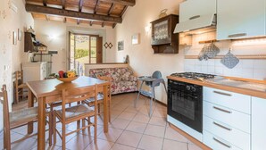 A cozy kitchen with wooden beams, a dining area with a table and chairs, and a sofa. - Apartment in Abetone with 2 bedrooms sleeps 4 (Abetone)