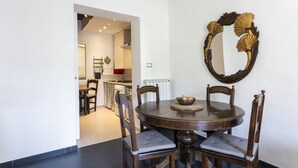 A dining area with a round table, four chairs, and a decorative mirror on the wall. - Serragli Retreat in Florence by Mmega (Firenze)