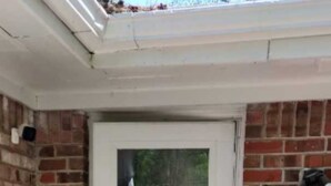 Una puerta blanca con un panel de vidrio, en una pared de ladrillo con un escalón que la precede.
