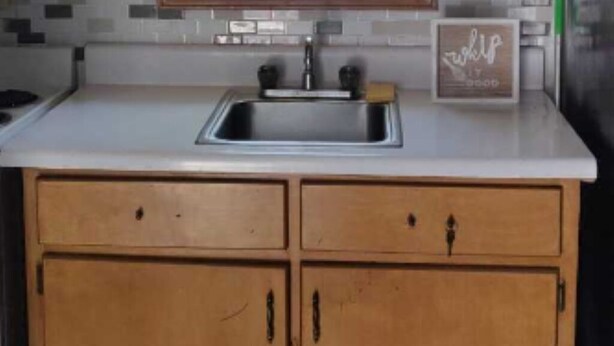 Una cocina con armarios de madera, un ventanal sobre el fregadero y un refrigerador de acero inoxidable.
