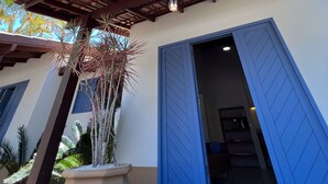 A covered outdoor area with a wooden ceiling and a blue door. - Vila Carijós (Florianópolis)