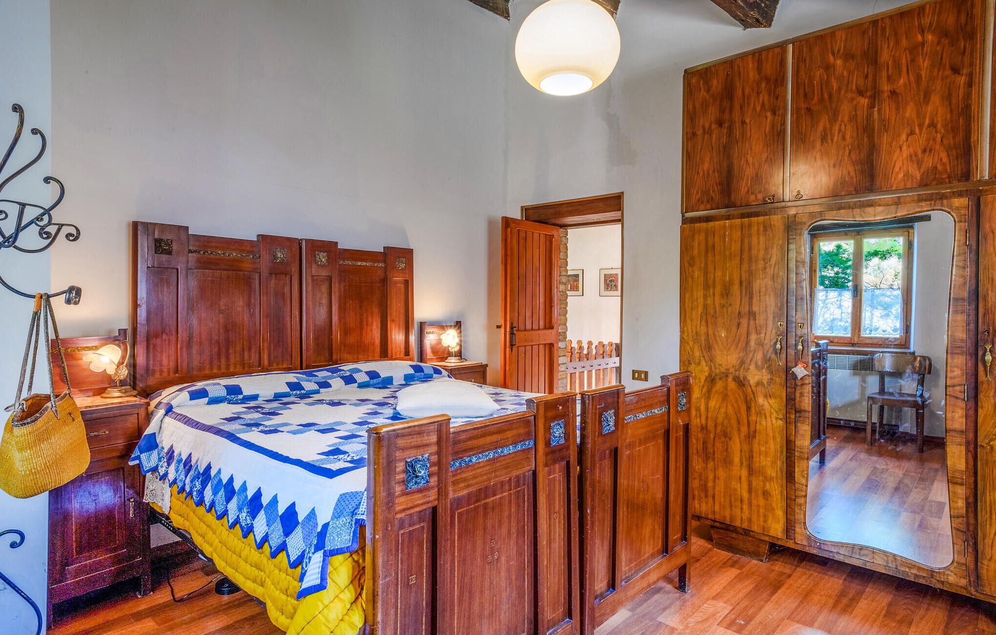 Une chambre à coucher avec un lit en bois, une table de chevet, une lampe et une armoire.