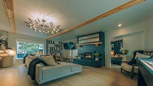 A modern living room with a fireplace, a large sofa, and a unique ceiling light fixture.