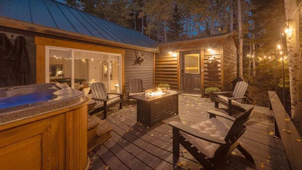 A wooden deck with outdoor seating, a hot tub, and a covered patio area.