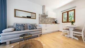A modern living room with a grey sofa, a round coffee table, and a dining area with a white table and chairs.