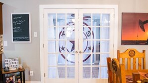 A room with a wooden floor, a white door with glass panels, a wooden chair, and a small table with a sign. - Wildcatter resting grounds, spacious living (Odessa)