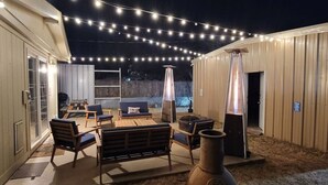 An outdoor patio area with string lights, a fire pit, and seating arrangements. - Wildcatter resting grounds, spacious living (Odessa)
