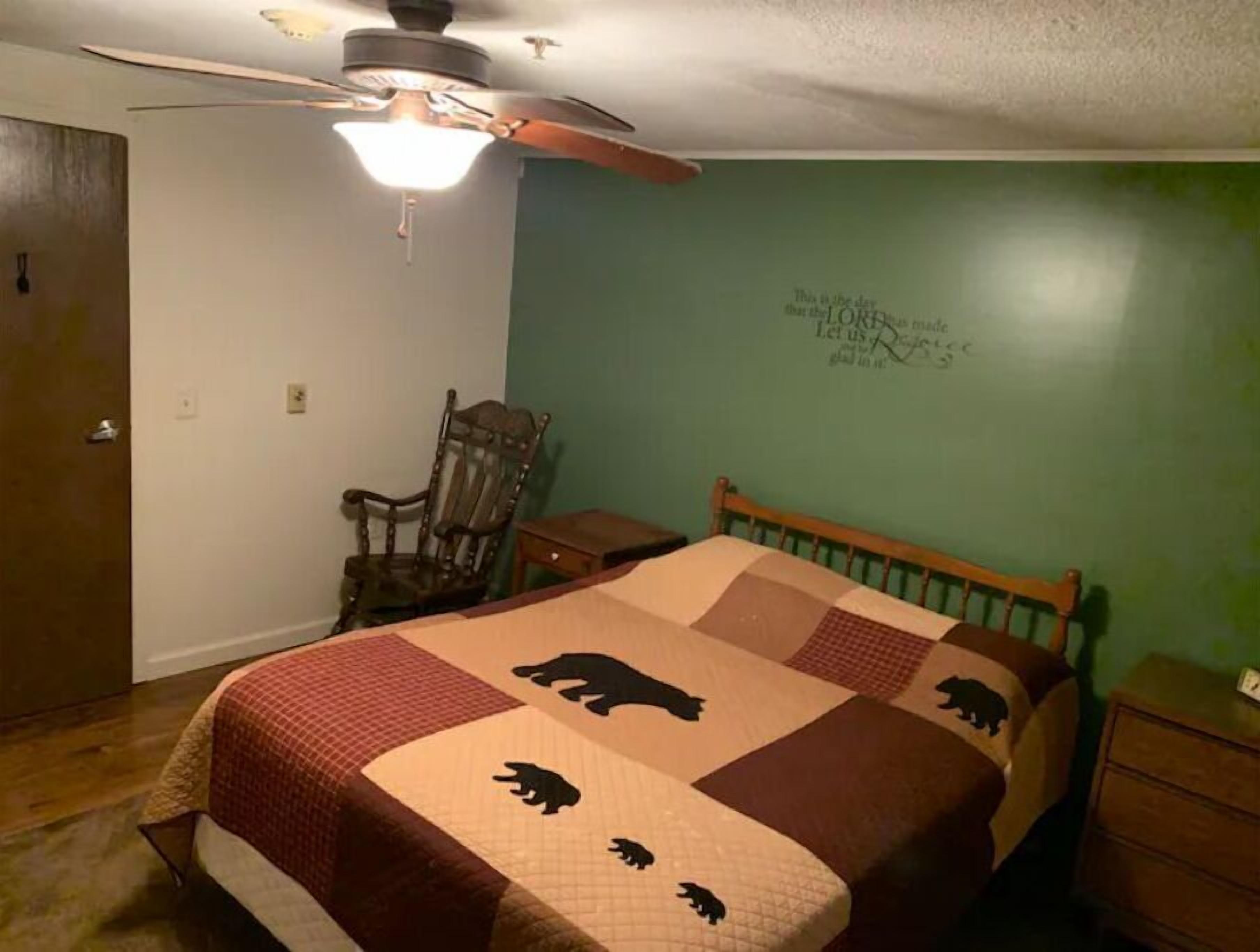 Une chambre à coucher comprenant un lit, un ventilateur de plafond, une chaise et une commode.