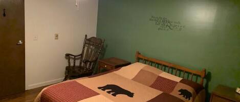 Une chambre à coucher comprenant un lit, un ventilateur de plafond, une chaise et une commode.