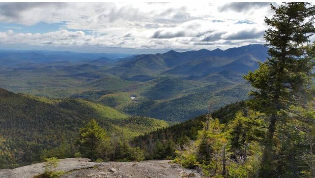 A mountainous landscape with dense forests and a clear sky.