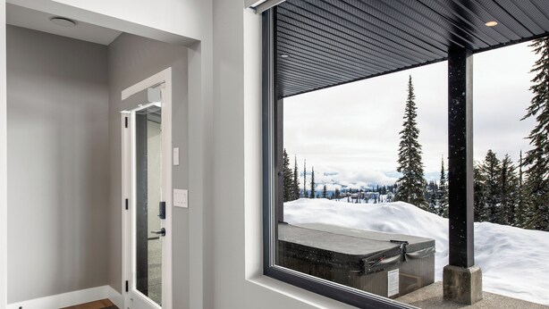 Un intérieur moderne avec une grande fenêtre donnant sur un paysage de montagne enneigé.
