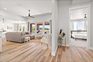 Un vaste espace de vie comprenant un grand canapé, des fauteuils et une table basse. De grandes fenêtres offrent une vue sur l’extérieur.