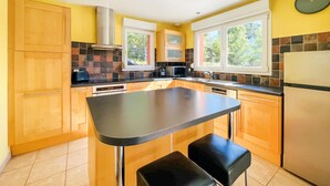 Una cocina con armarios de madera, una encimera negra, una campana extractora de acero inoxidable, un microondas y un refrigerador.
