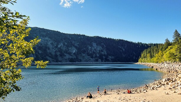 Un lago rodeado de terreno rocoso y un denso bosque.