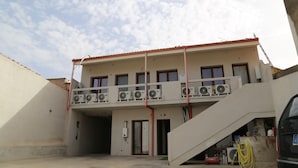 A two-story building with a balcony, air conditioning units, and a staircase leading to an entrance. - Al Civico 5 - Bright Apartment W/ Private Parking! (Decimomannu)