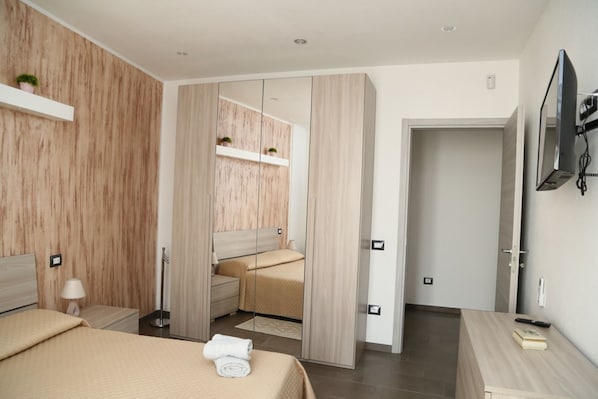 A modern bedroom with a bed, bedside table, lamp, and a TV mounted on the wall.