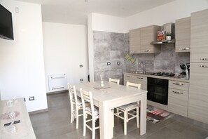 A modern kitchen with a dining table, chairs, a TV, and a built-in oven.