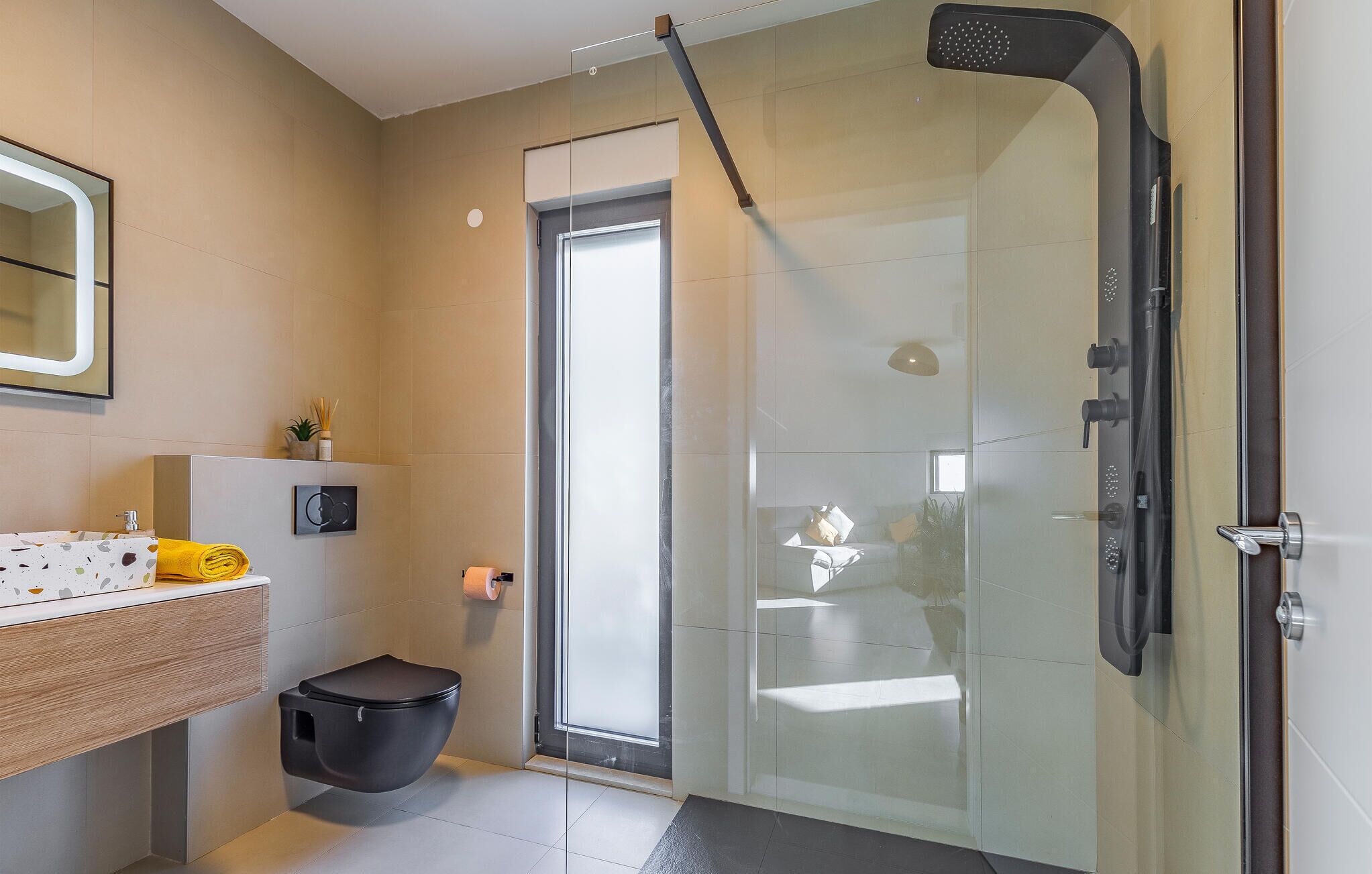 A modern bathroom with a glass shower enclosure, a toilet, a sink with a towel, and a mirror.