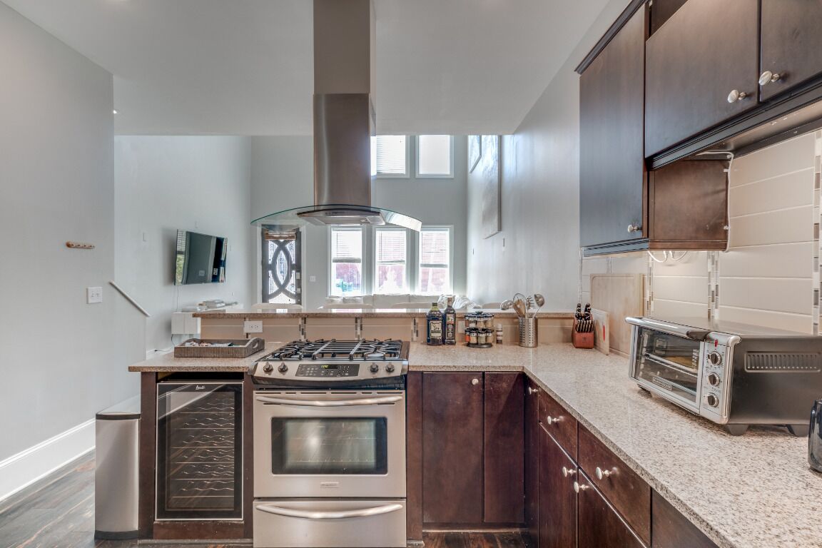 A modern kitchen with dark wood cabinets, stainless steel appliances, and a granite countertop.