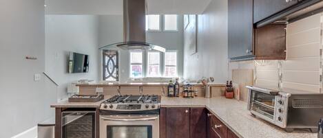 A modern kitchen with dark wood cabinets, stainless steel appliances, and a granite countertop.