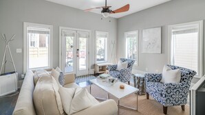 Un salon comprenant un canapé, deux fauteuils à motifs, une table basse et un ventilateur de plafond.