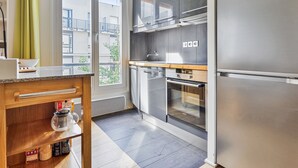 A modern kitchen with stainless steel appliances, a wooden countertop, and a view of the balcony. - Appartement Charenton - Welkeys (Paris)