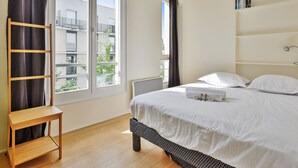 A bedroom with a bed, a wooden ladder, a window with curtains, and a view of buildings outside. - Appartement Charenton - Welkeys (Paris)