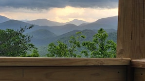 Un balcón de madera con vistas a un paisaje montañoso.