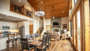 Una cocina amplia con electrodomésticos modernos, un comedor con sillas de madera y una mesa grande, y una chimenea de piedra.