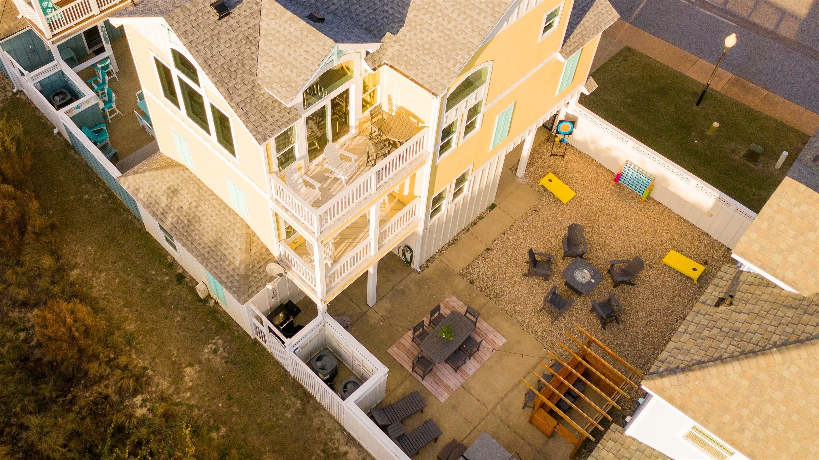 A multi-story house with a patio area, outdoor seating, and a small pool.