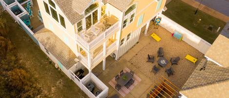A multi-story house with a patio area, outdoor seating, and a small pool.