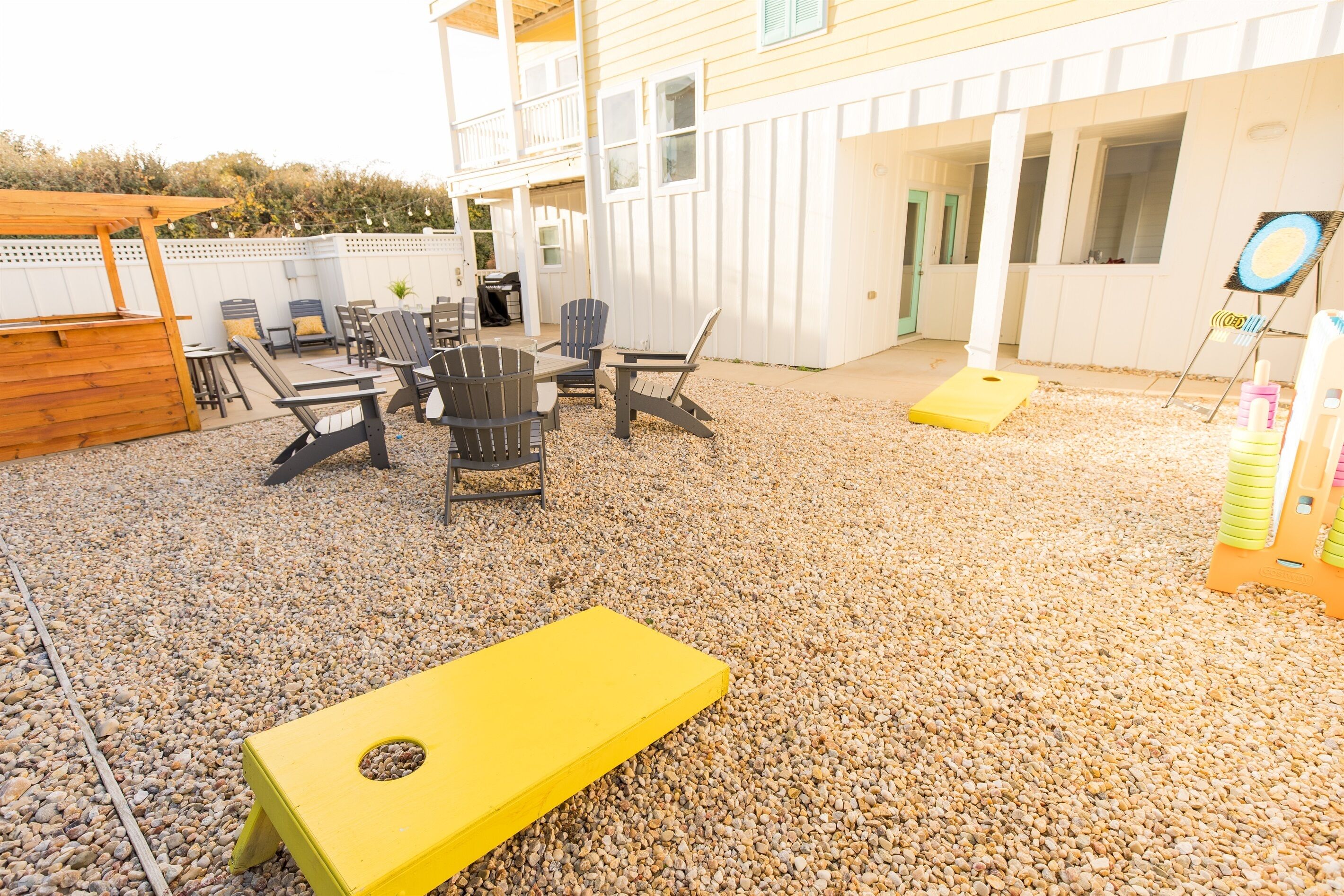 Un patio al aire libre con una zona de estar, un tapete amarillo y una pequeña estructura de madera.